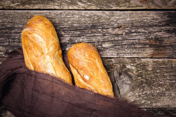 French baguette bread on old rustic wooden background. Crunchy freshly french bread. French bread sticks freshly out of the oven.