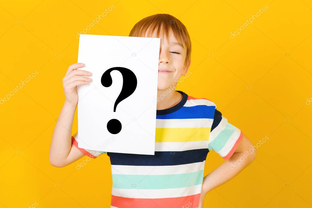 Cute little boy asking question. Kid ideas and brainstorm. Child with question mark. Schoolboy shows question mark. Brainstorming and choice concept. Curious child over yellow background.