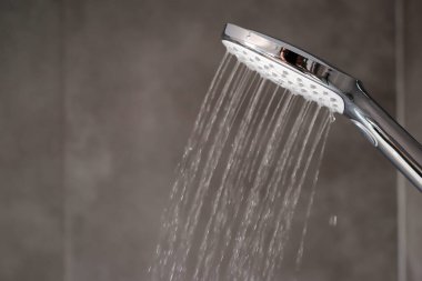Duştan akan su, kapat. Modern banyo içi. Su sıçratan krom duş başlığı. Modern duş başlığı. Banyoda su damlaları akan bir duş..