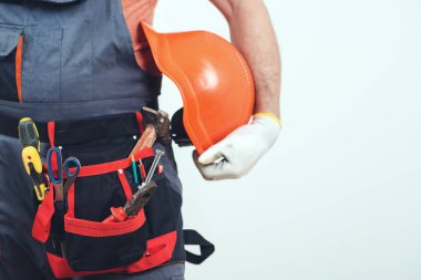 Aletleri olan profesyonel bir inşaatçı. Alet kemeri olan bir tamirci. Ev yenileme servisi. Aletleri olan inşaat işçisi. Endüstri Teması. İnsan yapımı sert şapka. Geliştirme ve yenileme.