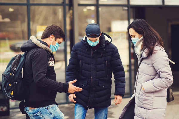 Global pandemic. Coronavirus disease. People in a medical mask outdoors. Coronavirus epidemic. Non-contact greeting. Coronavirus prevention. Foot shake style of greetings.