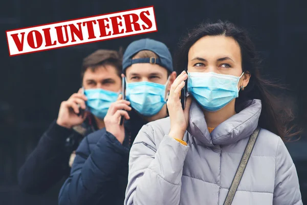 Young volunteers wearing face mask. Coronavirus epidemic. Volunteers with mobile phone. Global pandemic. Coronavirus quarantine. Volunteering concept. Prevention of epidemic of coronavirus.