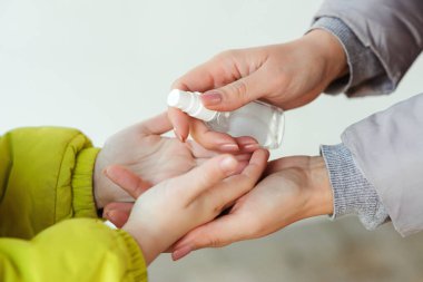 Aile, elleri temizlemek ve dezenfekte etmek için el dezenfektanı kullanıyor. Coronavirus 'a alkol spreyi sıkan bir kadın. Anne ve oğlu dezenfektan spreyi kullanıyor. İnsanlar ellerini antiseptik spreyle dezenfekte ediyor..