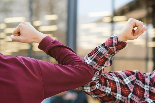 İki kişi dışarıda koronavirüsten korunmak için dirseklerini vurur. Coronavirüs salgını sırasında yeni bir selamlama şekli gösteriyorlar. Sağlık hizmeti konsepti. Sosyal uzaklık.