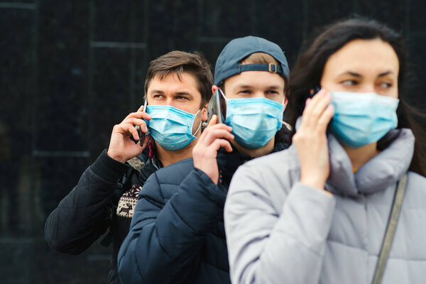 Volunteering. People wearing face mask outdoors. Worldwide coronavirus outbreak. Coronavirus epidemic. Global pandemic. Group of young volunteers with mobile phone. Coronavirus quarantine.