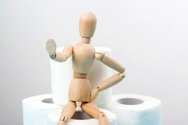 Stop panic. Wooden man sitting on a toilet paper rolls. Background with stock of toilet paper rolls. Coronavirus panic 2020. Coronavirus global pandemic. Coronavirus outbreak. People panic.