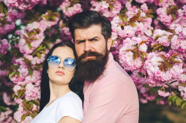 Bahar parkında sakallı bir adamla bir kadını sevmek. Bahar günü. Kiraz ağacının pembe çiçekleri. Taze pembe sakura çiçeği. Güzel kadın ve yakışıklı erkek arkadaşı dışarıda sarılıyorlar. Yaşam tarzı ve moda.
