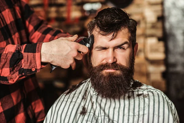 留胡子的英俊男子拜访美发师 理发店 留胡子的嬉皮士的发型 理发师剪胡子给男人看 男发型师服侍客人 理发师用机器和梳子理发 — 图库照片