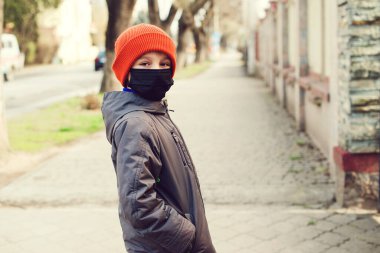 Sokakta yürüyen güvenlik maskeli bir çocuk. Coronavirus karantinası. Dünya çapında bir salgın. Hastalıktan korunmak için. Sağlık güvenliği kavramı. Çocuk dışarıda korunmak için yüz maskesi takıyor..