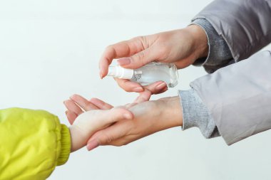 Aile, elleri temizlemek ve dezenfekte etmek için el dezenfektanı kullanıyor. Coronavirus 'a alkol spreyi sıkan bir kadın. Anne ve oğlu dezenfektan spreyi kullanıyor. İnsanlar ellerini antiseptik spreyle dezenfekte ediyor..