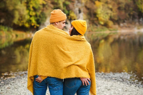 Couple in love in autumn nature. Lovers romantic date having fun together outdoors. Boyfriend with girlfriend on a walk near lake in autumn. Fashion couple, lifestyle and love. Autumn fashion.