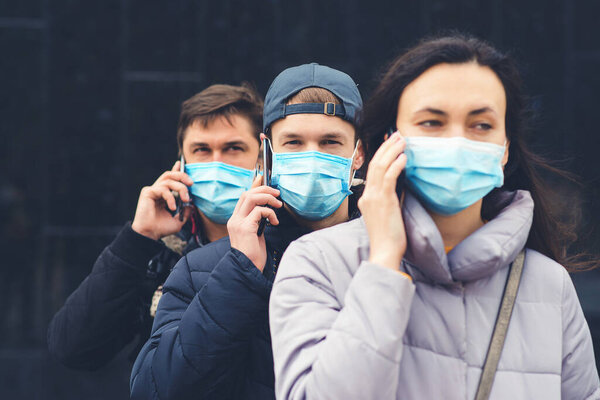 Group of young volunteers with mobile phone. Coronavirus quarantine. People wearing face mask outdoors. Global pandemic. Worldwide coronavirus outbreak. Coronavirus epidemic.
