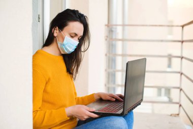 Freelancer, uzaktan kumanda. Coronavirus karantinası. Evden çalışıyorum. Karantinada çalışan bir kız. Karantina sırasında uzaktan eğitim. Balkonda dizüstü bilgisayarda çalışan bir kadın. Teknoloji, eğlence..