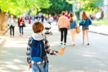 Çocuk dışarıda dondurma tutuyor. Güneşli bir günde parkta yürüyen bir çocuk. Açık havada şık bir çocuk. Lezzetli dondurma. Yaz tatili.
