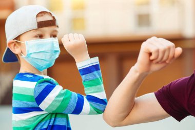 Küçük çocuk ve babası dirsekleriyle dışarıda selamlıyorlar. Coronavirus önleme. Dirsek hareketi. Aile, yaşam tarzı, yeni selamlaşma tarzı. Coronavirus karantinası. Sosyal uzaklık kavramı. Aile.