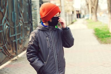 Çocuk dışarıda korunmak için yüz maskesi takıyor. Sokakta yürüyen güvenlik maskeli bir çocuk. Coronavirus karantinası. Dünya çapında bir salgın. Hastalıktan korunmak için. Sağlık güvenliği kavramı.