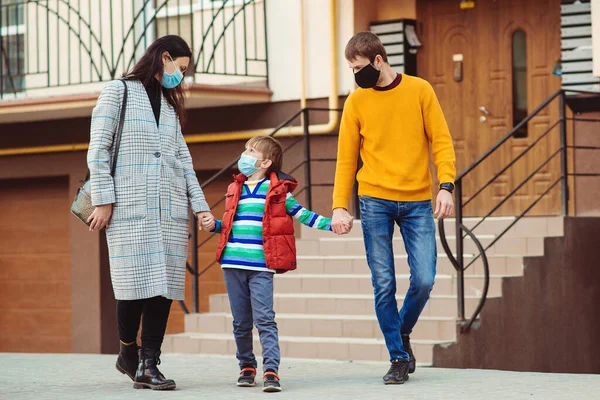 Family going for a walk. Parents and kid wearing a surgical mask. Air pollution concept. Young family wearing protection face mask outdoors. Prevention coronavirus. Coronavirus quarantine.