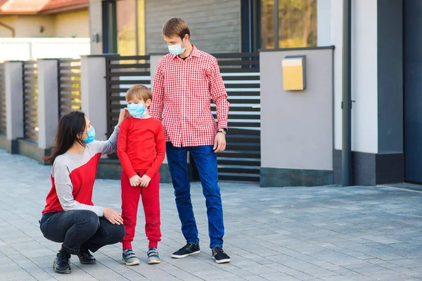 Family wearing face masks outside home. Safety mask to protect coronavirus outbreak. Prevention coronavirus. Son with parents going for a walk. New real life. Fight coronavirus. Coronavirus quarantine.