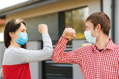 Kız ve erkek dışarıda dirseklerle selamlaşıyor. Yeni gerçek hayat. Coronavirus karantinası. Coronavirüs salgını. Güvenlik maskeli arkadaşlar dışarıda. Genç çift dışarıda yüz maskesi takıyor. Sosyal uzaklık.