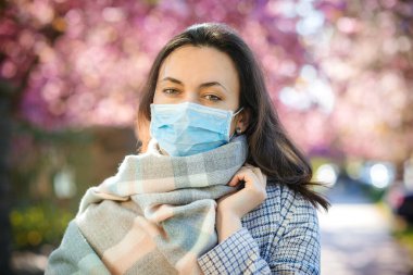 Dışarıda maske takan bir kadın. Koronavirüsü önlemek için güvenlik maskesi. Coronavirüs salgını. 2020 baharında. Salgın sırasında gerçek hayat. Coronavirus önleme. Sokakta şık bir kadın..