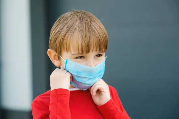小さな男の子の顔保護マスクを屋外に置く コロナウイルスの発生 徒歩でコロナウイルス インフルエンザ ウイルスの保護のための安全マスクを身に着けている子供 コロナウイルスの隔離 — ストック写真