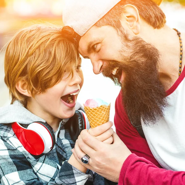 Cute kid boy eating an ice cream in a cone. Father and son having fun together. Summer vacation. Tasty fruit ice cream for family. Father and son have a great time on a walk.