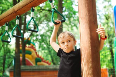 Küçük çocuk ip macera parkında oynuyor. Çocuk halat parkında barfiks çekiyor. Sağlıklı yaşam tarzı kavramı. Çocuklar için modern eğlence parkı. Açık hava oyunları. Mutlu çocuk halat tırmanma ağında