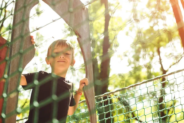 ケーブルトンネルを通っている少年 屋外遊び場 子供のためのレジャー 幸せな子供時代 アドベンチャーパークでの極端なスポーツ 夏休みだ かわいい少年はロープクライミングネットに登る アドベンチャーロープパーク — ストック写真