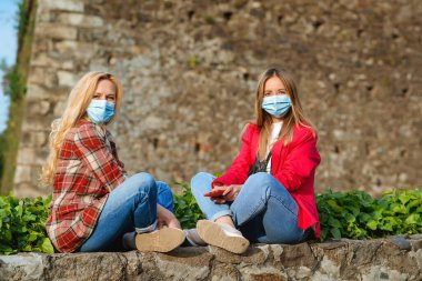 Arkadaşlar Coronavirus salgını sırasında eski şatoda seyahat ederler. Yaz tatilleri karantina altında. Avrupa seyahati. Dışarıda maskeli iki kız. Yaşam tarzı, seyahat 2020. Arkadaşlık kavramı.