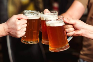 Barda bira içen arkadaşlar. Erkekler barda soğuk bira bardaklarıyla tost kaldırıyor. Erkekler bira içer. Arkadaşlar için bira partisi. Boş zaman, arkadaşlık ve kutlama. İnsanlar barda dinleniyor..