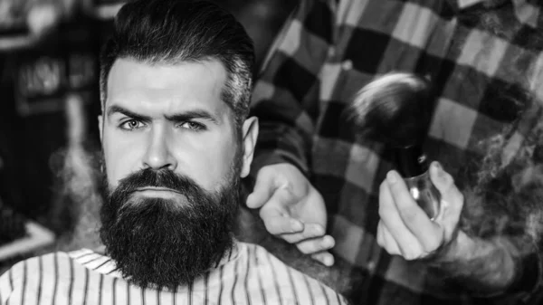 Bearded man getting haircut by hairdresser. Brutal guy sitting in barber chair. Vintage barbershop, business. Man making haircut to look perfect. Stylish bearded man in salon. New perfect style.