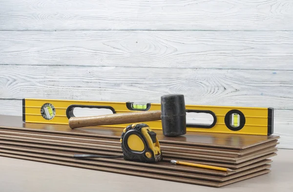 Carpentry concept.Different tools- level,tape-measure,rubber hammer on the new laminate flooring.Copy space for text. — Stock Photo, Image