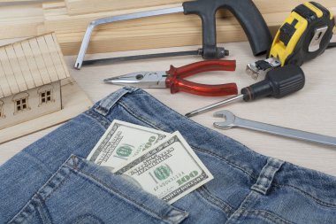İnşaat ve iş kavramı. Farklı çalışma araçları, dolar ahşap arka plan üzerinde kot pantolon cebinde.
