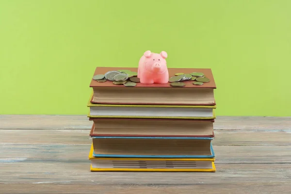 Κουμπαράς με βιβλία και τα κέρματα σε ξύλινο υπόβαθρο. Έννοια της χρηματοδότησης της εκπαίδευσης. — Φωτογραφία Αρχείου