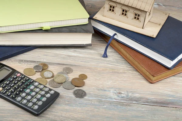 Ahorro en el hogar, concepto de presupuesto. Casa modelo, bloc de notas, calculadora y monedas en mesa de oficina de madera — Foto de Stock