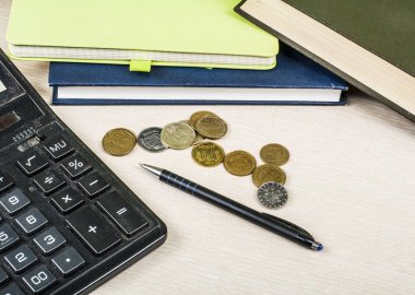 Ev tasarruf, bütçe kavramı. Not Defteri, kalem, hesap makinesi ve sikkeler üzerinde ahşap ofis masaları.