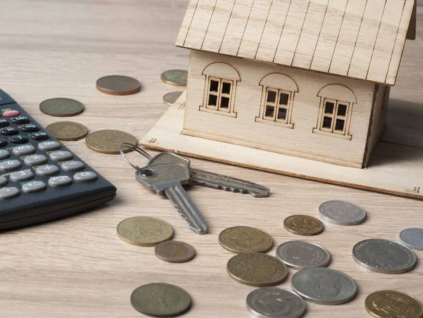 Ahorro en el hogar, concepto de presupuesto. Casa modelo, llaves, calculadora y monedas en mesa de oficina de madera . — Foto de Stock