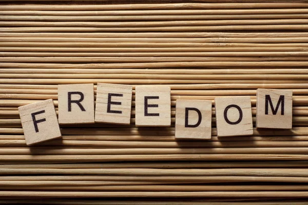 FREEDOM word written on wood abc cubes at wooden background
