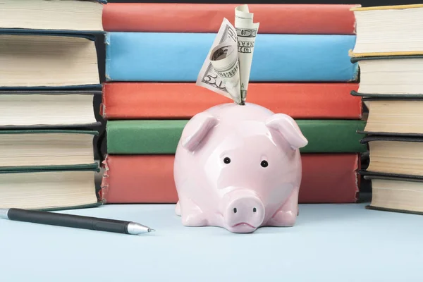 Ροζ κουμπαράς με βιβλία και χρήματα σε ξύλινο υπόβαθρο. Έννοια της χρηματοδότησης της εκπαίδευσης. — Φωτογραφία Αρχείου