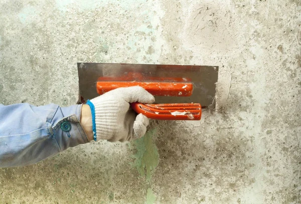 Conceito de construção e renovação. Mão de homem em luva com espátula durante o reparo de parede . — Fotografia de Stock