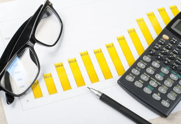 Poupança doméstica, conceito de orçamento. Gráfico, caneta, calculadora e óculos na mesa de mesa de escritório de madeira — Fotografia de Stock
