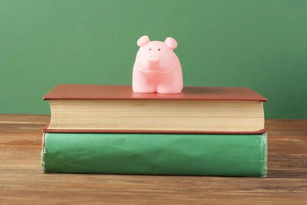 Κουμπαράς με βιβλία σε ξύλινο υπόβαθρο. Έννοια της χρηματοδότησης της εκπαίδευσης. — Φωτογραφία Αρχείου