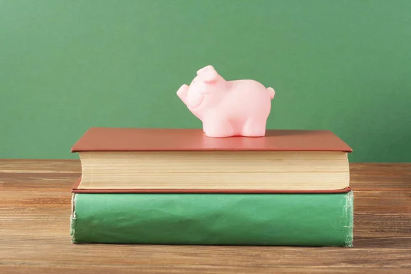 Ροζ κουμπαράς με βιβλία σε ξύλινο υπόβαθρο. Έννοια της χρηματοδότησης της εκπαίδευσης. — Φωτογραφία Αρχείου