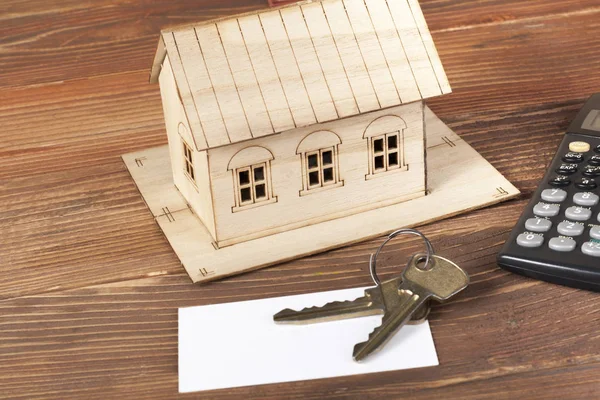 Strona główna oszczędności, koncepcja budżetu. Modelu dom, kalkulator i klucze na podłoże drewniane. — Zdjęcie stockowe