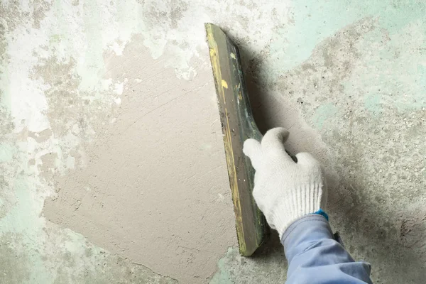 Construction and renovation concept. Hand of man in glove with trowel during repair of wall. — Stock Photo, Image