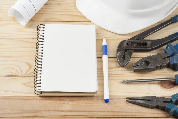 Bauwerkzeuge, weißer Helm, Notizblock und Stift auf hölzernem Hintergrund. Kopierplatz für Text. — Stockfoto