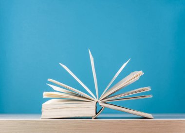 Ahşap masa mavi zemin üzerine açık kitap. Okula dönüş. Metin için yer kopyalayın.