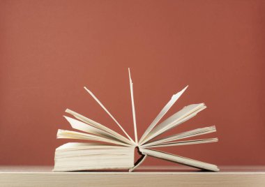 Açık kitap üzerinde kırmızı zemin üzerine ahşap masa. Okula dönüş. Metin için yer kopyalayın.