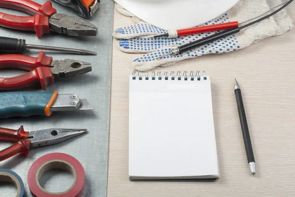 .Conjunto de herramientas eléctricas, casco blanco y bloc de notas sobre fondo metálico. Concepto energético . — Foto de Stock