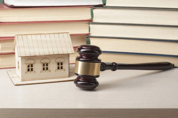 Law concept. Miniature house, books with wooden judge gavel on table in a courtroom or enforcement office.